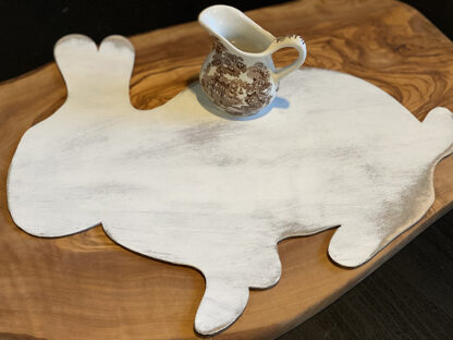 wood cut shaped bunny painted white and distressed with a brown and white transferware creamer placed on top