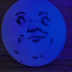 Round wood with man on the moon face that is glow in the dark